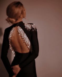 the back of a woman's black dress with silver sequins on it