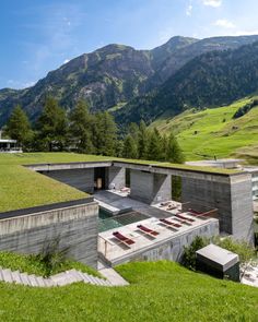 an outdoor swimming pool in the middle of a grassy area with mountains in the background