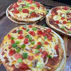 three pizzas with different toppings sitting on top of a wooden table next to each other