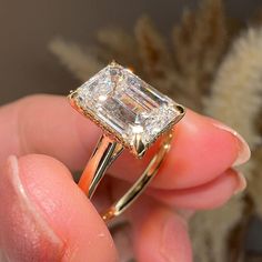 a person holding an engagement ring with a diamond in it's middle and the other hand