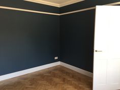 an empty room with blue walls and white trim on the door, wood flooring