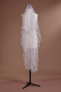 a white veil on a mannequin stand with a light brown background in the corner