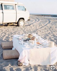 a table set up on the beach with an suv in the background