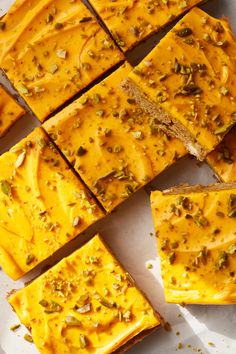 slices of pumpkin cheesecake with pistachio toppings cut into squares on a white surface