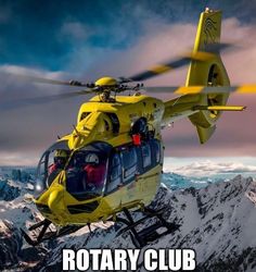 a yellow helicopter flying over snow covered mountains