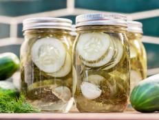 three mason jars filled with pickles and cucumbers