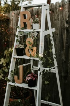 a white ladder with plants and letters on it