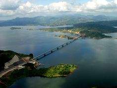 an aerial view of a bridge spanning the width of a large body of water with mountains in the background