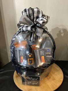 a gift basket is sitting on top of a wooden plate with black and white ribbon