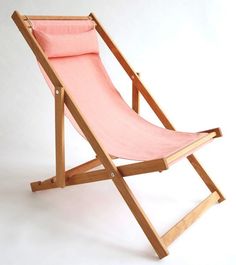 a pink beach chair sitting on top of a white floor next to a wooden frame