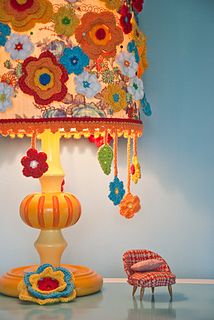 a lamp that is on top of a table next to a small chair and ottoman