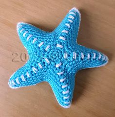 a blue crocheted starfish sitting on top of a wooden table with the number 20 written in white