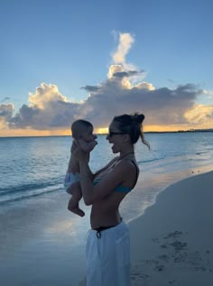 a woman holding a baby on the beach