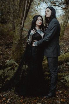 a man and woman standing next to each other in the woods