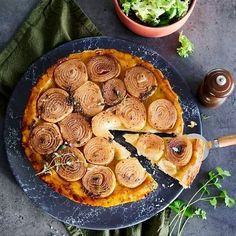 a pizza on a blue plate with a slice missing from it next to a potted plant