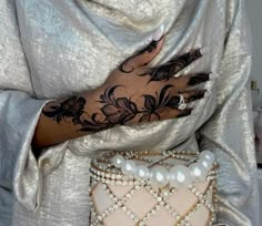 a woman's hand with tattoos on it and pearls around the wrist, sitting next to a purse