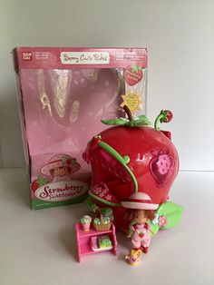 a strawberry shortcake playset with its box and contents on the table next to it