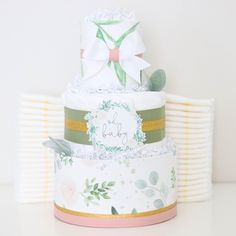 three tiered baby shower cake with flowers and leaves on the top, sitting on a table