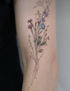 a woman's arm with flowers and leaves on the left side of her body