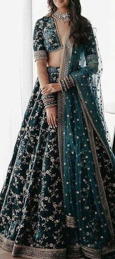 a woman in a blue and green lehenga is posing for the camera with her hands on her hips