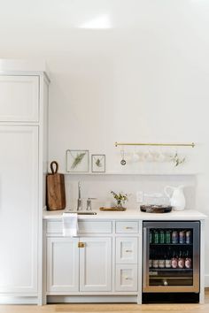 a kitchen with white cabinets and an open wine cooler in the middle of the room