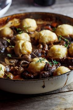 a pot filled with stew and dumplings on top of a wooden table