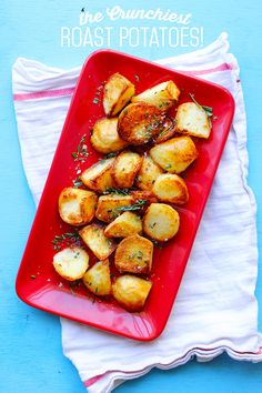 a red plate topped with potatoes on top of a white cloth next to a blue wall