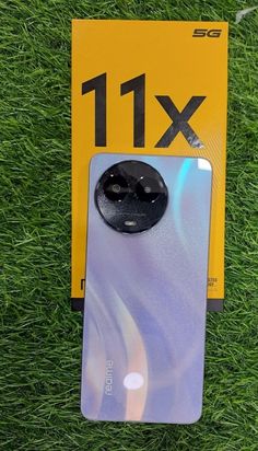 the back of an iphone 11x in its packaging on some green grass with a black button