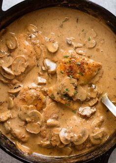 a skillet filled with chicken and mushrooms covered in gravy