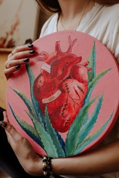 a woman holding a painted heart on a pink plate