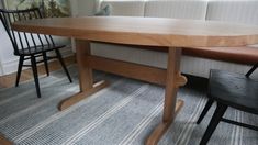 a wooden table sitting next to two black chairs on top of a carpeted floor