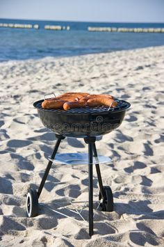 hot dogs are cooking on the grill in the sand at the beach royalty images and stock photography