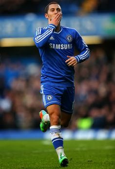 a soccer player is running on the field with his hand to his face as he looks up