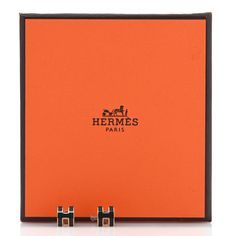 an orange box with two black square studs on it and the words hermes paris