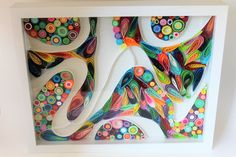 an art piece made out of paper with circles and shapes on the bottom, in a white frame