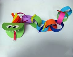 a paper snake is attached to a colorful necklace with colored streamers on it's neck