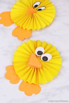 two yellow paper fans with googly eyes and an orange bird's head on them