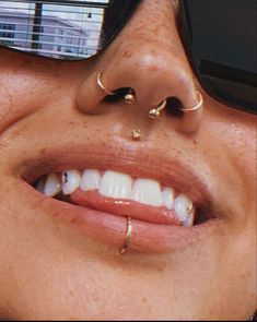 a close up of a person wearing sunglasses and piercings