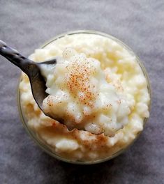 a spoon full of mashed potatoes with cinnamon sprinkles in a glass bowl