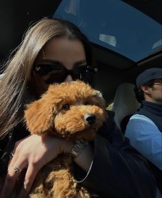 a woman holding a dog in her arms while sitting in the back seat of a car