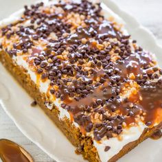 a piece of cake on a plate with chocolate chips and caramel drizzle