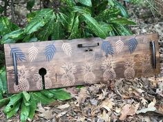 a wooden sign with pineapples on it in front of some leaves and bushes