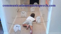 a young boy laying on the floor in front of paper ghost decorations