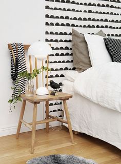 a bed room with a neatly made bed and a night stand next to it on a hard wood floor