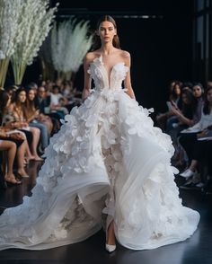 a model walks down the runway in a white gown with ruffles on it