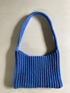 a blue knitted bag sitting on top of a white table next to a wall