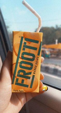 a person holding up a carton of frooti from the back seat of a car