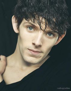 a close up of a person wearing a black shirt with his hand on his shoulder