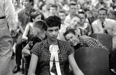 two women sitting next to each other in front of a large group of men and women