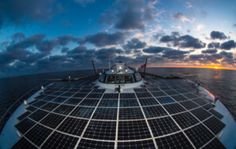 the sun is setting over the ocean with many solar panels on it